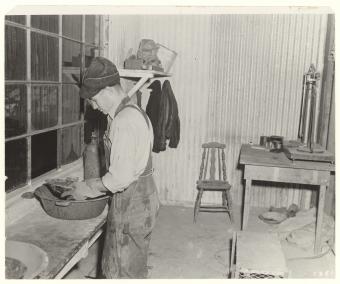 A man wearing overalls performs a pan test in a rough laboratory.
