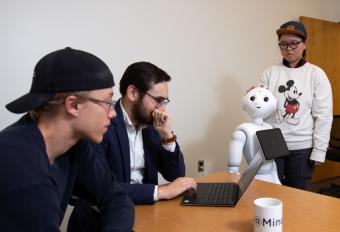 Assistant Professor Tom Williams with students and robot