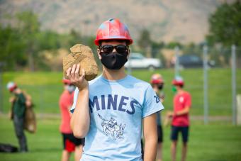 Male student holds rock before M Climb