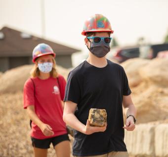 Two Mines students carry rocks to temporary M