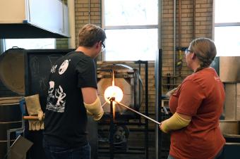 Male and female student making glass
