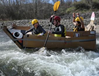 Three students in cardboard boat