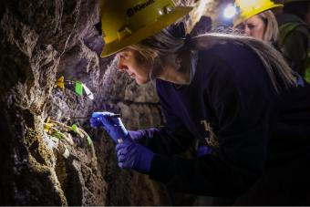 Student wearing hardhat collecting sample underground