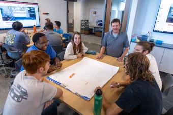 Table of students talks to professor during Design I