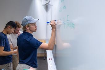 Three students work problems on the board