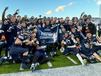 Football team poses with 2023 Road to National Championship banner