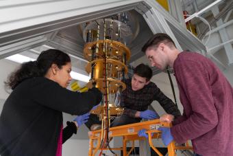 Female professor works with two male students on dilution refrigerator