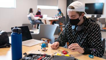 Masked student works on project in the new McNeil Hall