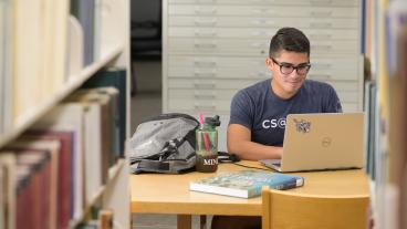 Male student works on computer in library