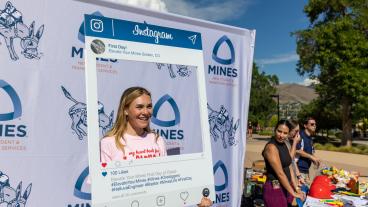 Mines student poses with Instagram backdrop