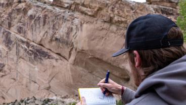 Student takes notes of rock formation near Massadona