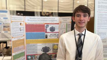 Male high school student stands in front of research poster board