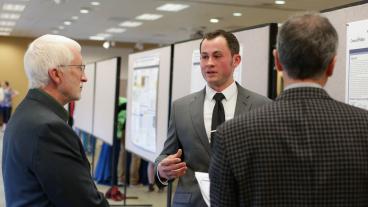 Dean Kevin Moore and another judge listen to a poster presentation.