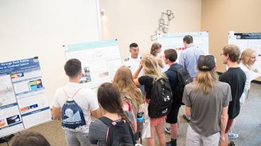 Undergraduate students present their research at the summer REU poster session.