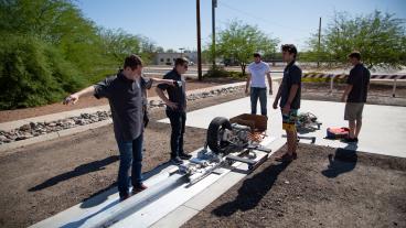 DiggerLoop team members size up the pod on the test track at Arizona State University earlier this summer.