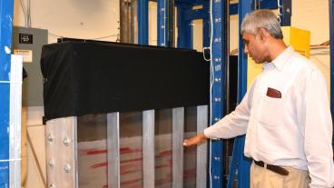 Civil and Environmental Engineering professor Tissa Illangasekare motions toward one of the larger tanks that he uses to study soil concentrations.